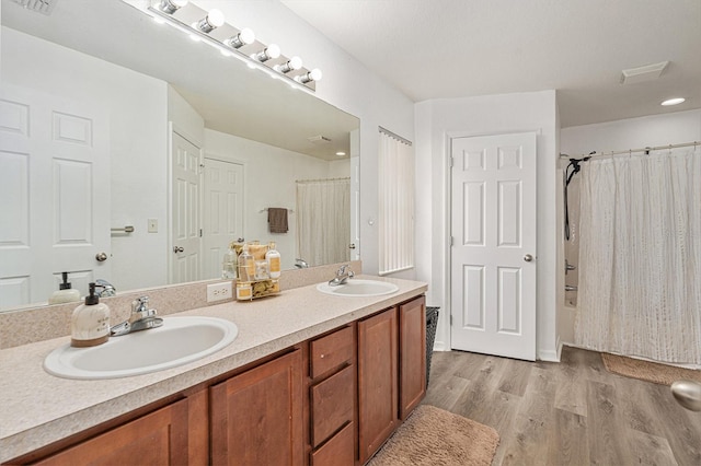 bathroom with hardwood / wood-style flooring, vanity, and shower / bathtub combination with curtain