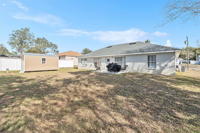 back of property with a storage shed, a yard, and a patio