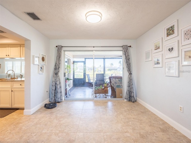 interior space with light tile patterned flooring, sink, and a textured ceiling