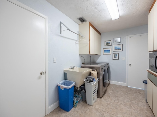 laundry room featuring cabinets, sink, a textured ceiling, and independent washer and dryer