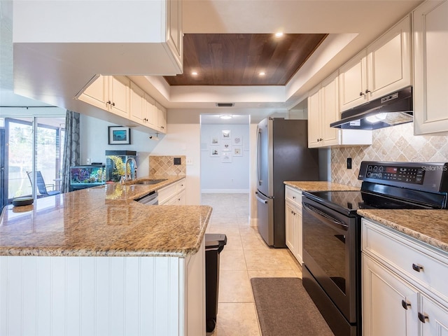 kitchen featuring appliances with stainless steel finishes, tasteful backsplash, white cabinetry, light tile patterned floors, and a tray ceiling