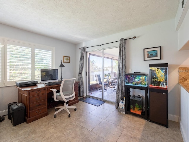 home office featuring light tile patterned floors, a wealth of natural light, and a textured ceiling