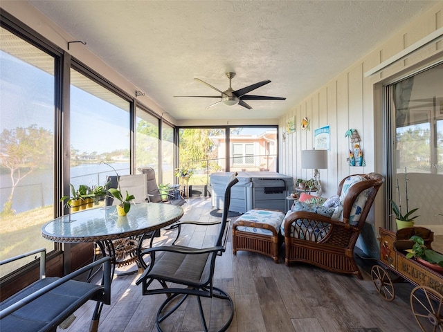 sunroom featuring ceiling fan, a healthy amount of sunlight, and a water view