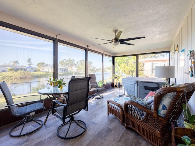 sunroom featuring a water view and ceiling fan