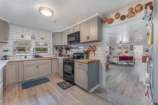 kitchen with gray cabinets, backsplash, black appliances, and light wood-type flooring