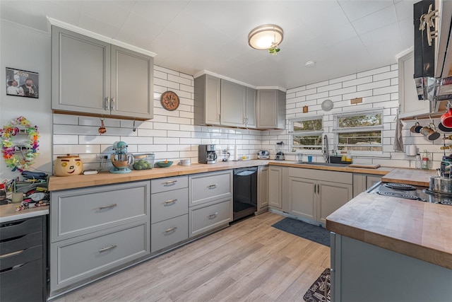 kitchen featuring gray cabinets, decorative backsplash, light wood-type flooring, dishwasher, and sink