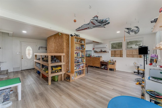 game room featuring a healthy amount of sunlight, a wall mounted AC, and light wood-type flooring