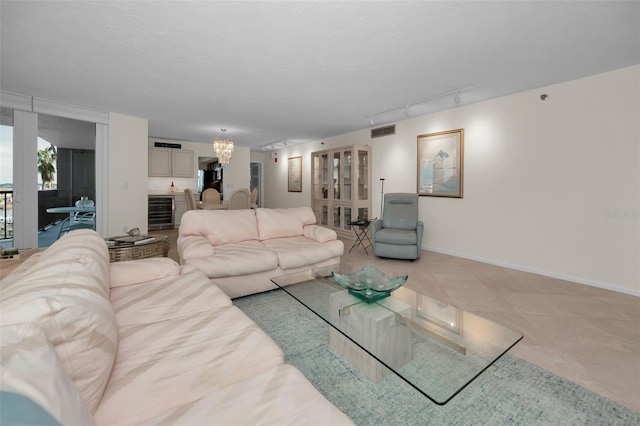 living room featuring light tile patterned flooring, beverage cooler, an inviting chandelier, and rail lighting