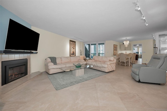 living room featuring light tile patterned floors, rail lighting, a fireplace, and a notable chandelier