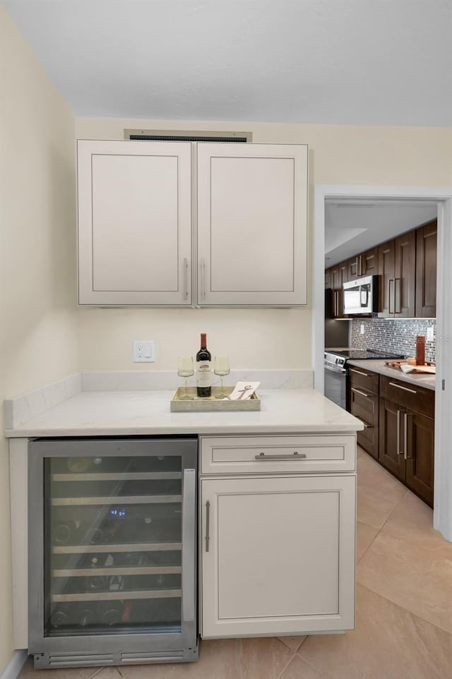 bar featuring wine cooler, dark brown cabinets, light tile patterned flooring, and electric range oven