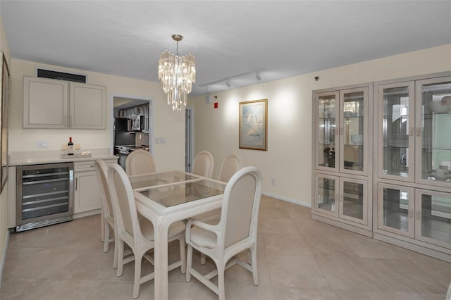 tiled dining room featuring an inviting chandelier, rail lighting, and wine cooler