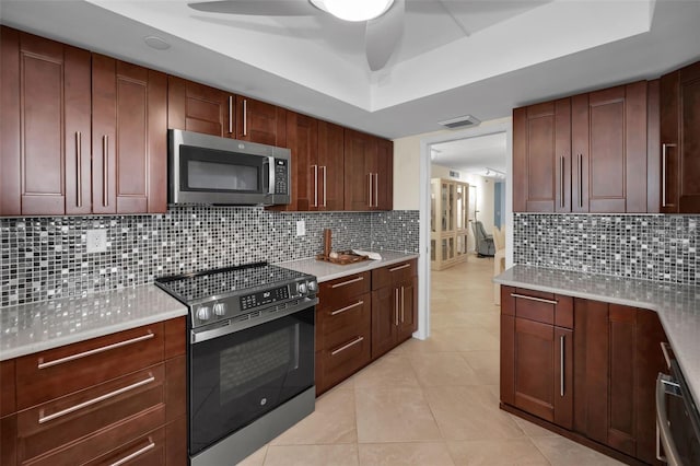 kitchen with tasteful backsplash, light tile patterned floors, stainless steel appliances, and a raised ceiling