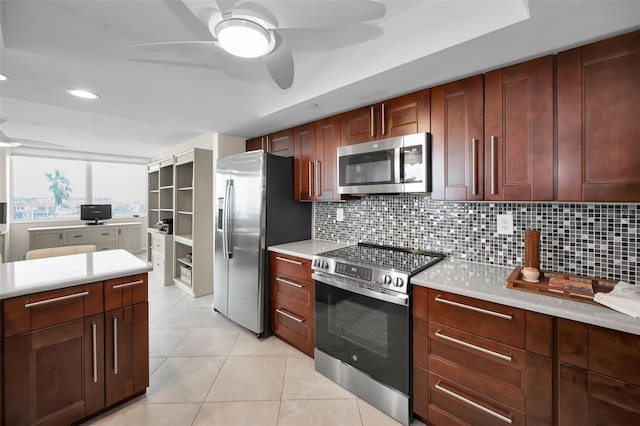 kitchen with stainless steel appliances, tasteful backsplash, a raised ceiling, ceiling fan, and light tile patterned floors