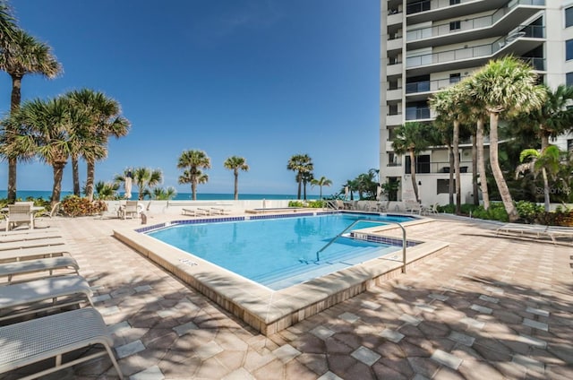 view of swimming pool featuring a water view and a patio