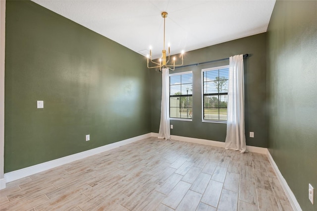 unfurnished room with a chandelier and light hardwood / wood-style flooring