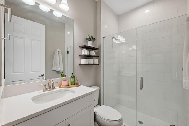 bathroom featuring a shower with door, vanity, and toilet