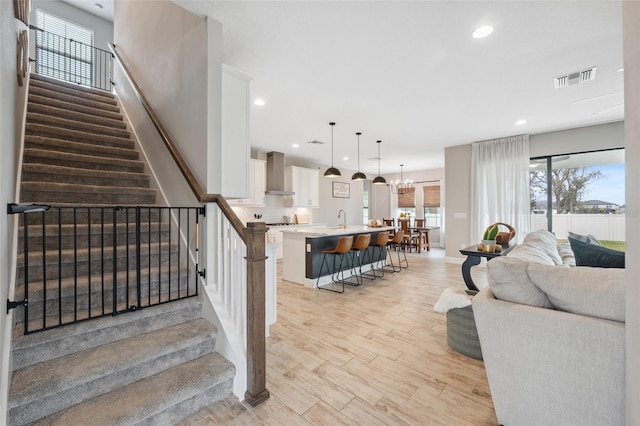 living room with sink, light hardwood / wood-style flooring, and a notable chandelier