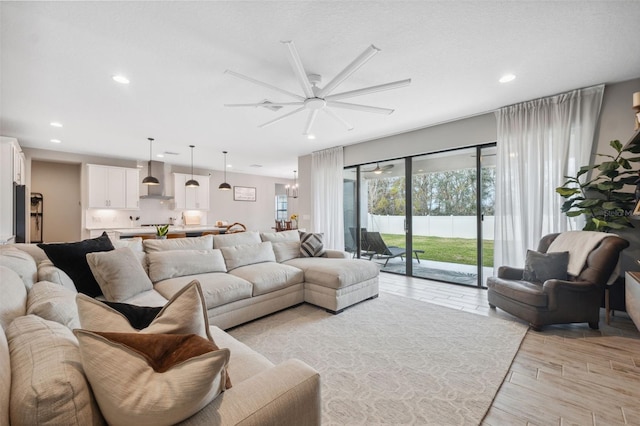 living room featuring ceiling fan with notable chandelier and light wood-type flooring