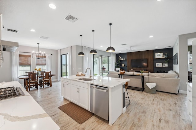 kitchen featuring sink, decorative light fixtures, appliances with stainless steel finishes, light stone countertops, and white cabinets