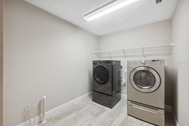 laundry area with washing machine and dryer and light hardwood / wood-style flooring