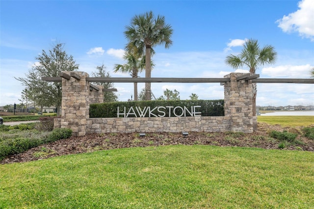 community sign featuring a water view and a lawn