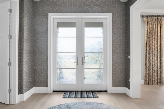 doorway to outside with a wealth of natural light, french doors, and light wood-type flooring