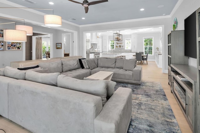 living room with plenty of natural light, sink, light hardwood / wood-style flooring, and ornamental molding