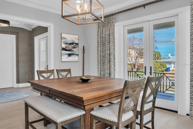 dining room with a notable chandelier, french doors, crown molding, and light hardwood / wood-style floors