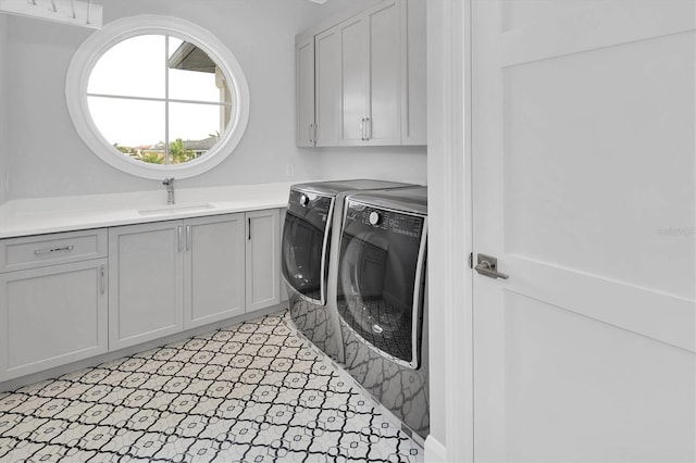 clothes washing area with cabinets, sink, and independent washer and dryer