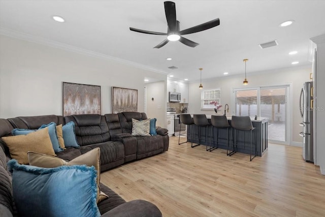 living room with crown molding, sink, ceiling fan, and light hardwood / wood-style flooring