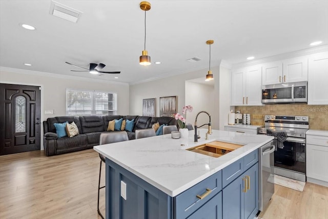 kitchen with sink, decorative light fixtures, white cabinets, and appliances with stainless steel finishes