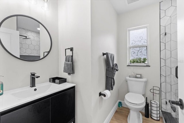 bathroom with hardwood / wood-style flooring, vanity, walk in shower, and toilet