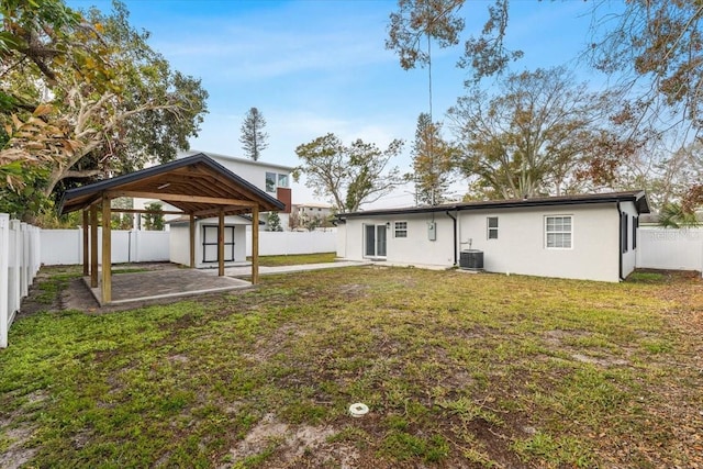 rear view of property featuring a shed, cooling unit, a yard, and a patio