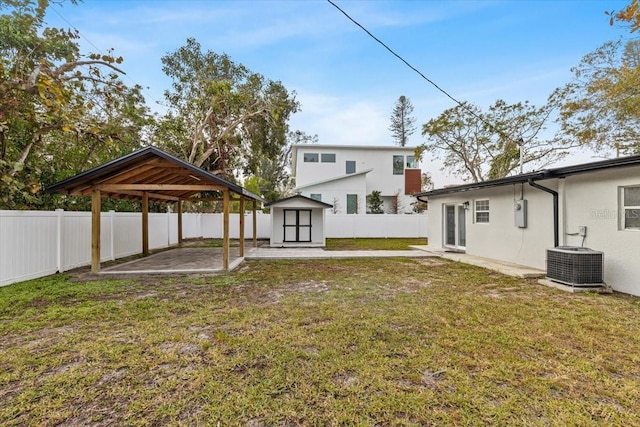 rear view of property featuring a lawn, cooling unit, a gazebo, a patio area, and a storage shed