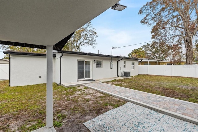 rear view of property featuring a patio, cooling unit, and a lawn