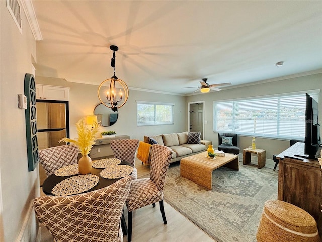 living room with a healthy amount of sunlight, ceiling fan with notable chandelier, ornamental molding, and light hardwood / wood-style floors