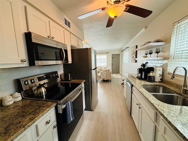 kitchen featuring white cabinetry, stainless steel appliances, tasteful backsplash, stone countertops, and sink