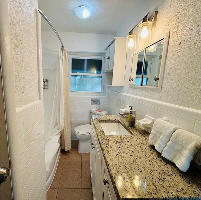 full bathroom with toilet, vanity, tile patterned flooring, tile walls, and shower / bath combo