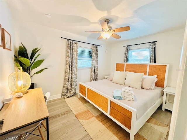 bedroom featuring ceiling fan, multiple windows, and light wood-type flooring