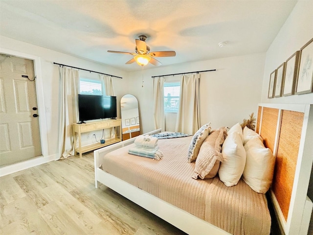 bedroom with light wood-type flooring, ceiling fan, and multiple windows