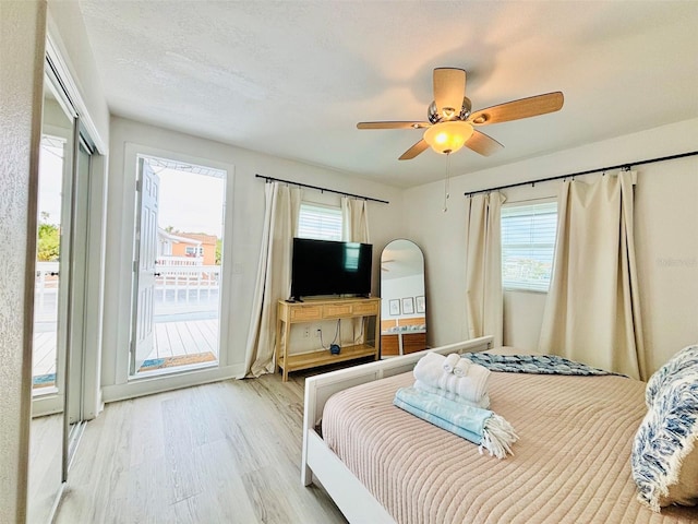 bedroom featuring ceiling fan, access to exterior, a textured ceiling, and light hardwood / wood-style flooring