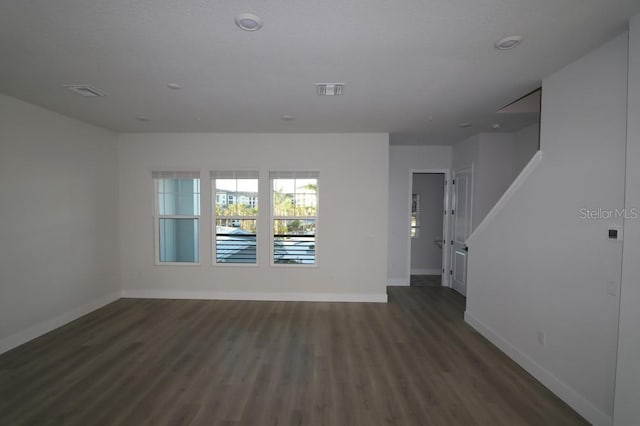 unfurnished room with visible vents, baseboards, and dark wood-type flooring