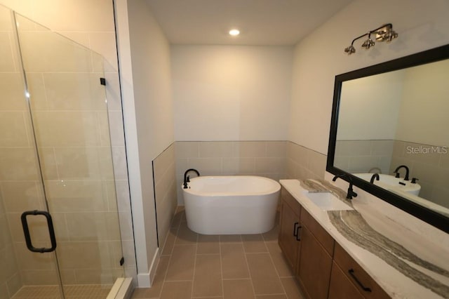 bathroom featuring a stall shower, a sink, tile patterned flooring, double vanity, and a soaking tub