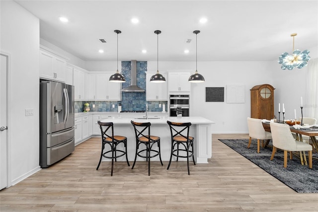 kitchen featuring appliances with stainless steel finishes, pendant lighting, and wall chimney range hood