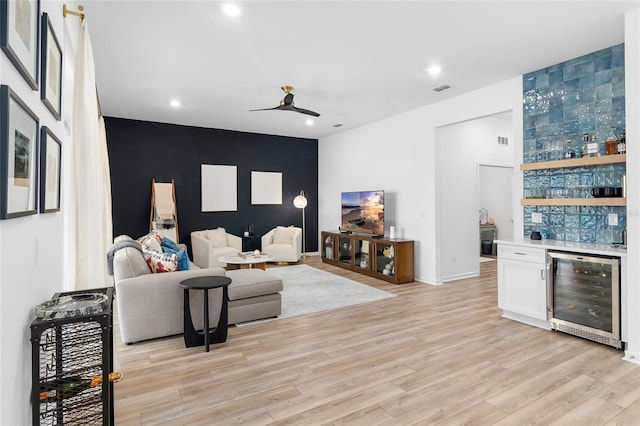 living room featuring bar, ceiling fan, light hardwood / wood-style floors, and beverage cooler