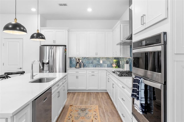 kitchen with decorative light fixtures, white cabinets, sink, and stainless steel appliances