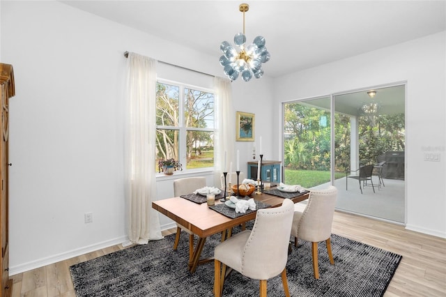 dining room with light hardwood / wood-style floors and a notable chandelier