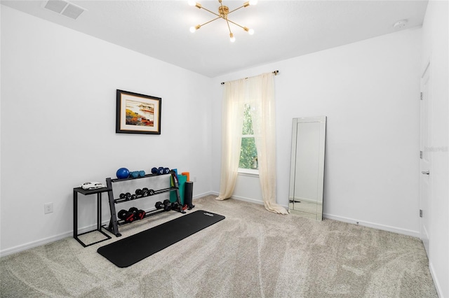 exercise room featuring a chandelier and light colored carpet