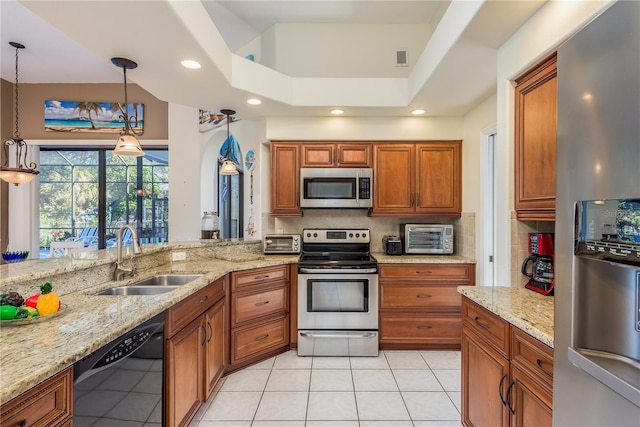 kitchen with sink, light stone counters, decorative light fixtures, appliances with stainless steel finishes, and decorative backsplash