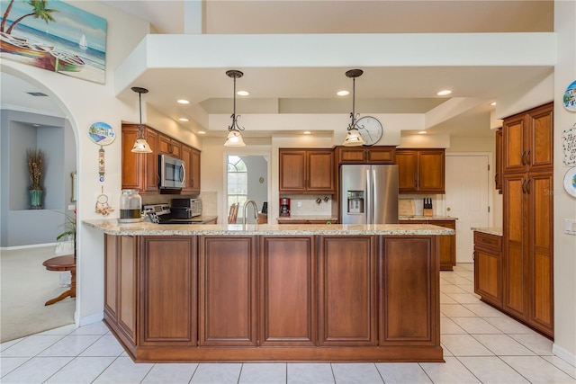 kitchen featuring sink, light stone counters, decorative light fixtures, kitchen peninsula, and stainless steel appliances